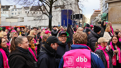 Eine Gruppe Menschen in pinken Warnwesten demonstriert auf einem öffentlichen Platz