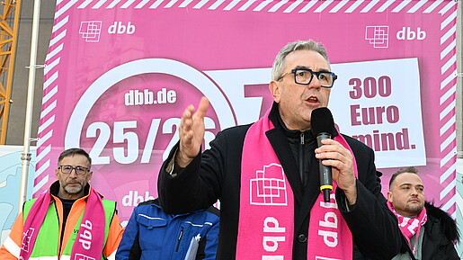 Ein Mann steht bei einer Demonstration auf einer Bühne und spricht in das Mikrofon
