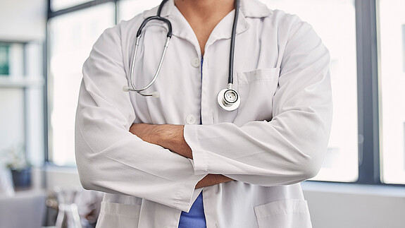 Gesundheitswesen ist Daseinsvorsorge und kein Sparposten Das Foto zeigt einen Arzt, er hat die Arme verschränkt.
