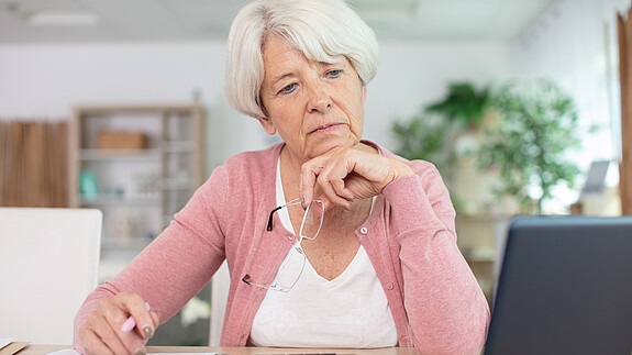 FAQ - Aktivrente und Einbeziehung von Beamten Foto zum Thema "Aktivrente und Einbeziehung von Beamten": Zu sehen ist eine Seniorin, die am Rechner sitzt und arbeitet.