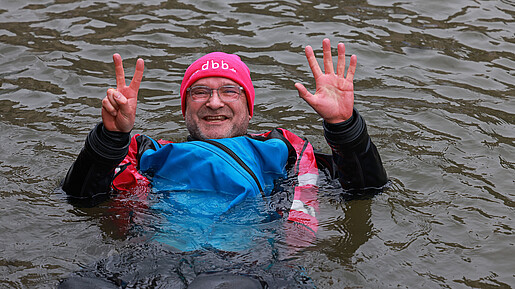 Ein Mann in Neoprenanzug badet in einem Fluss