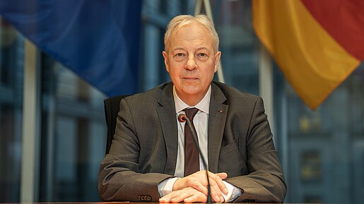 Markus Töns sitzt vor der deutschen und europäischen Flagge