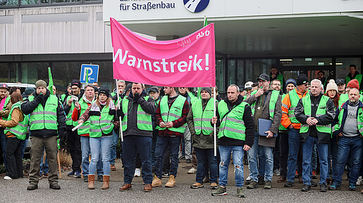 Das Foto zeigt demonstrierende Straßenwärter. Sie tragen grüne Streikwesten.