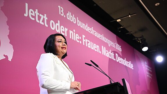 Eine Frau steht auf einer Bühne und spricht in ein Rednerpult