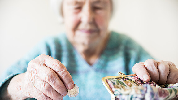 Altersarmut ist weiblich Eine unglücklich wirkende Seniorin zählt am Tisch die wenigen Münzen ihre Pension.