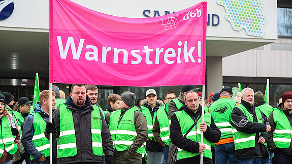 Das Foto zeigt demonstrierende Straßenwärter. Sie tragen grüne Streikwesten.