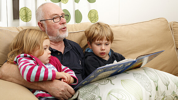 Alphabetisierung: Lesen Sie vor! people, person, scandinavian, adult, child, male, man, senior, grandfather, grandparent, girl, boy, grandchild, group, age, 60, 3, 5, sitting, sofa, inside, indoors, livingroom, home, daylight, family, generation, togetherness, love, harmony, loving, reading, book, story, telling, enjoying, feeling, tenderness, happiness, happy, joyful, joy, entertainment, entertaining, blond, grey, casual, relaxed, relaxing, lifestyle, wellness