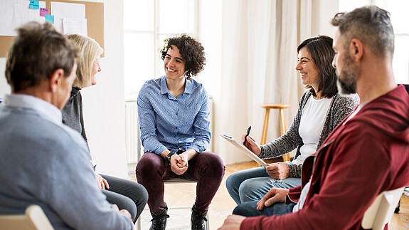 Am 19. März 2024 ist Tag der Sozialen Arbeit. indoors, inside, group, therapy, session, mental, support, counseling, meeting, circle, health, help, psychologist, advice, talking, rehab, psychotherapy, patient, caucasian, therapist, professional, listening, counselor, problem, guidance, office, together, psychological, psychiatrist, psychotherapist, disorder, people, adults, men, women, males, females, young, old, holding, supporting, each other, sitting, serious, client, counselling, counsellor