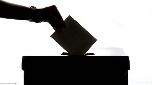 Ein Wahlschein wird in die Wahlurne eingeworfen
