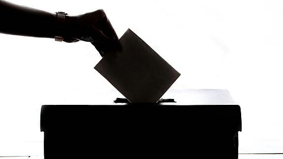 Ein Wahlschein wird in die Wahlurne eingeworfen